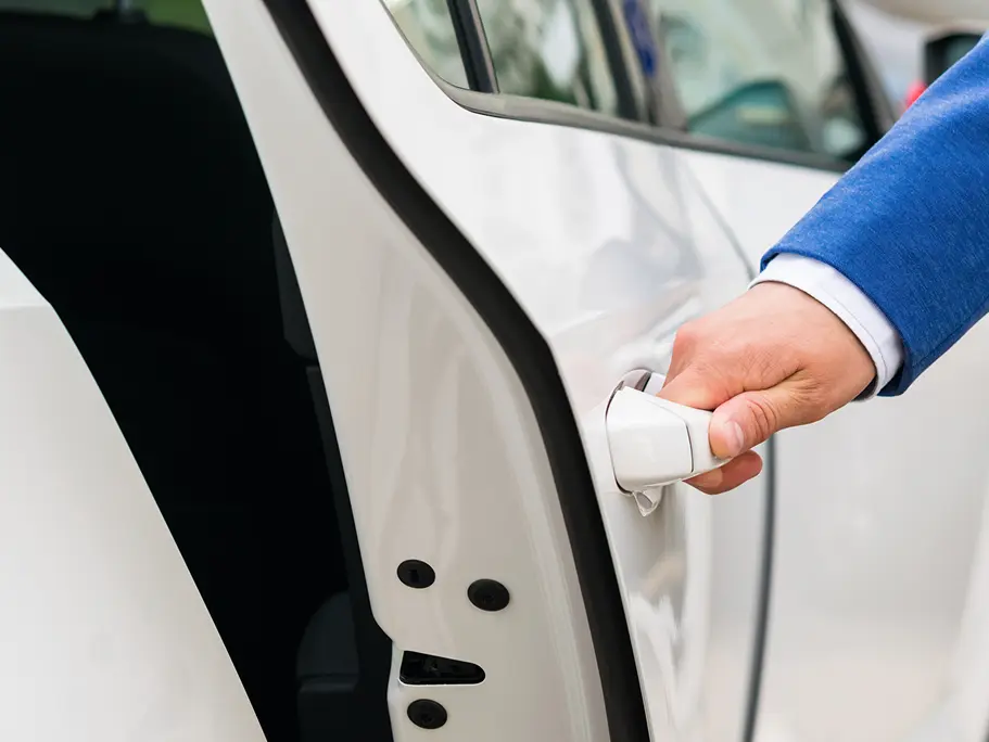 The person's hand holds the handle of the car door and opens the car, close-up